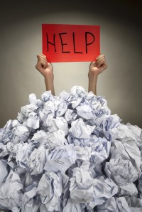 Hands with red frame reaches out from big heap of crumpled papers