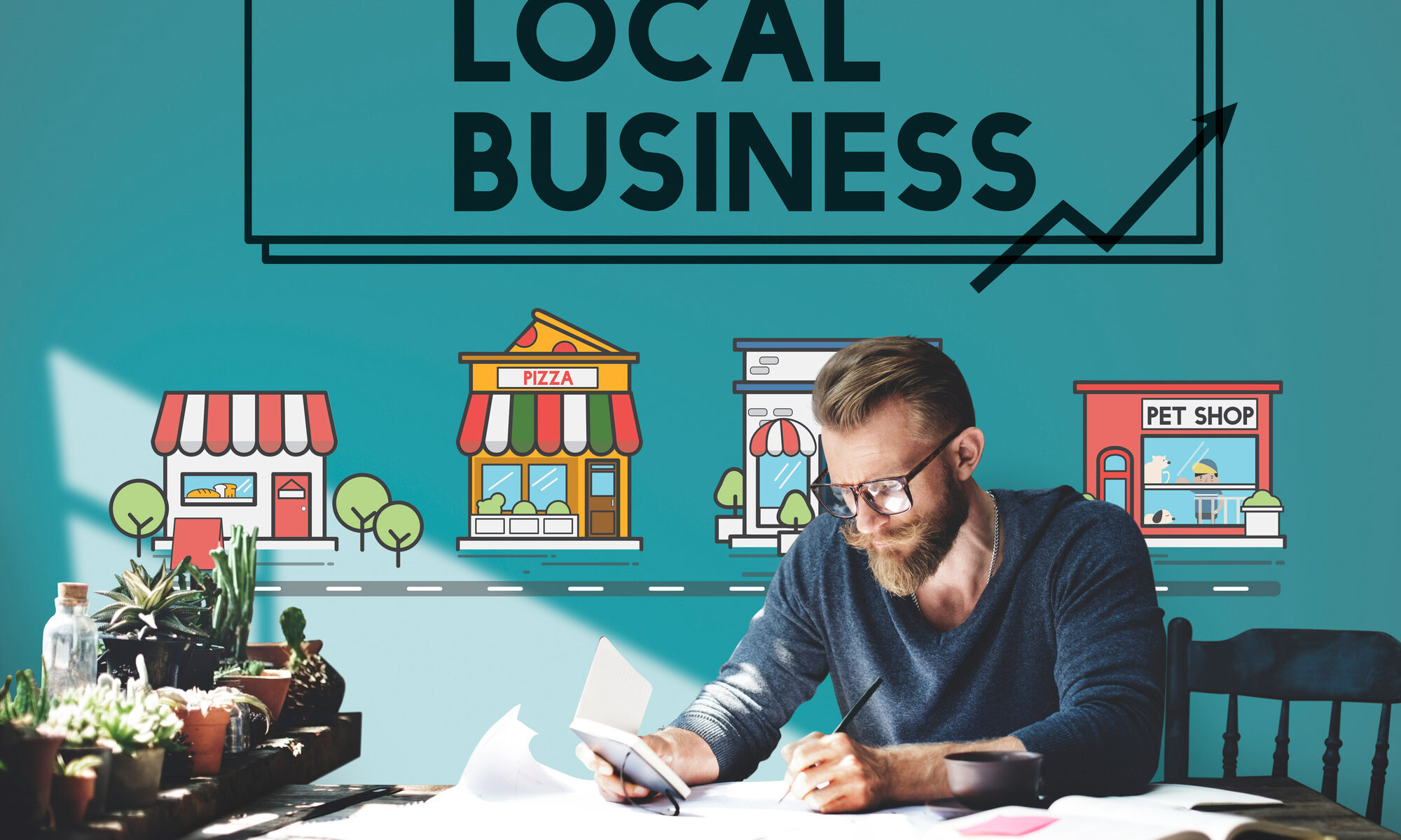 Man sitting under a banner which says local business at a desk.